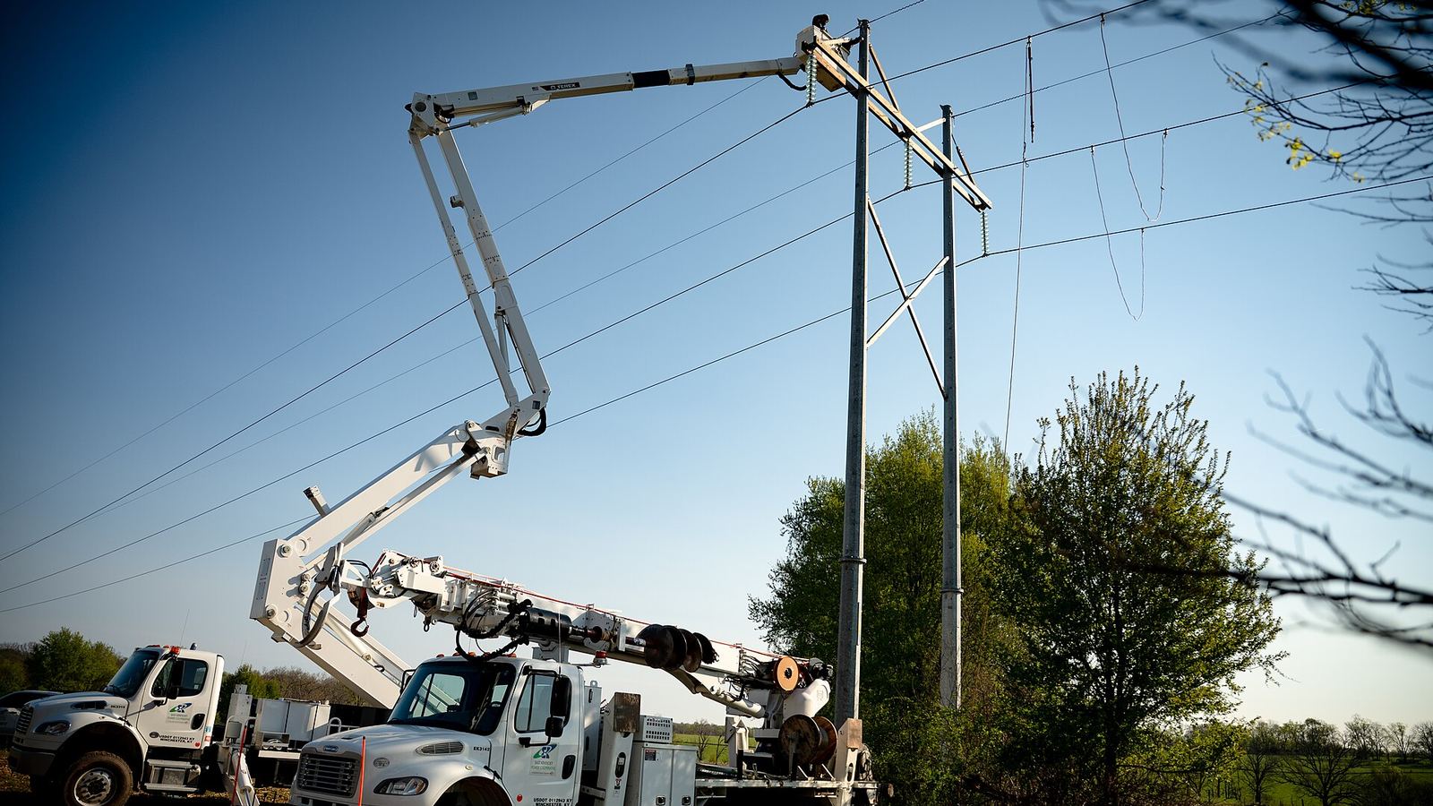 Camiones con canasta trabajando en una estructura de la red eléctrica